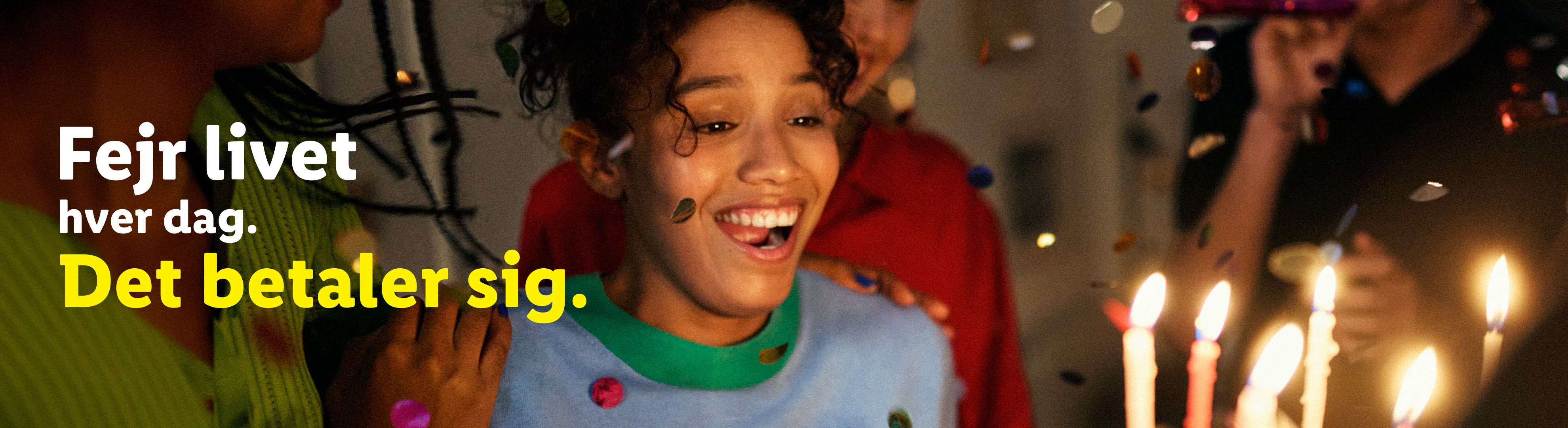 En ung kvinde smiler ved et fødselsdagsbord med tændte lys og konfetti. Tekst: Fejr livet hver dag. Det betaler sig.