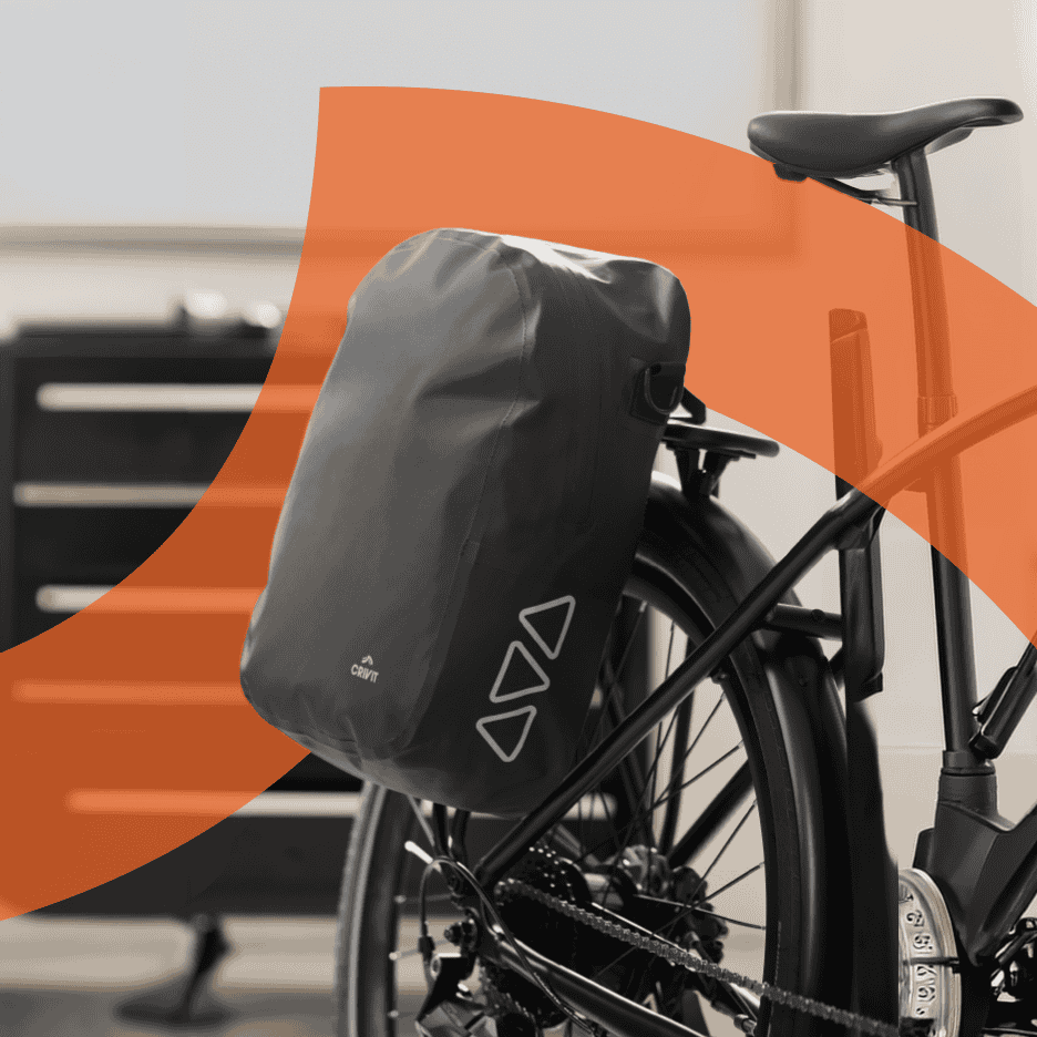 Cykel med en sort vandtæt taske monteret på bagagebæreren, med reflekterende trekanter.