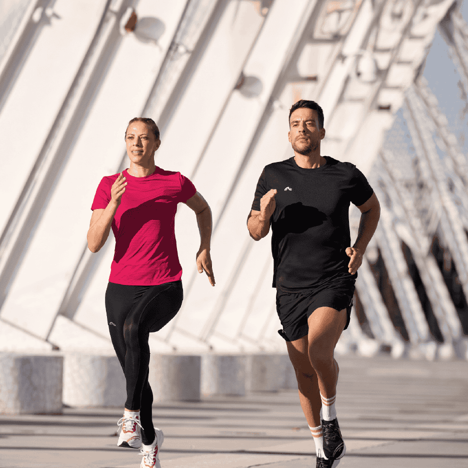 To løbere i sportstøj, en kvinde i pink t-shirt og sorte leggings, en mand i sort t-shirt og shorts.