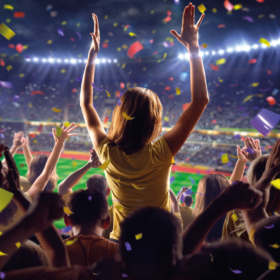 Jublende publikum i et stadion med konfetti og lys.