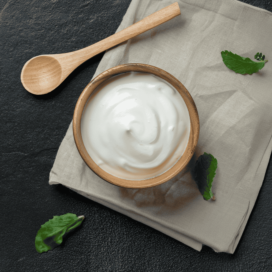 Skål med yoghurt, træske og mynteblade på en dug.