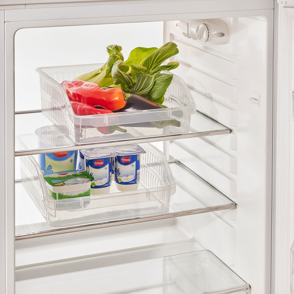 Køleskab med gennemsigtige opbevaringsbokse fyldt med grøntsager, yoghurt og ost.
