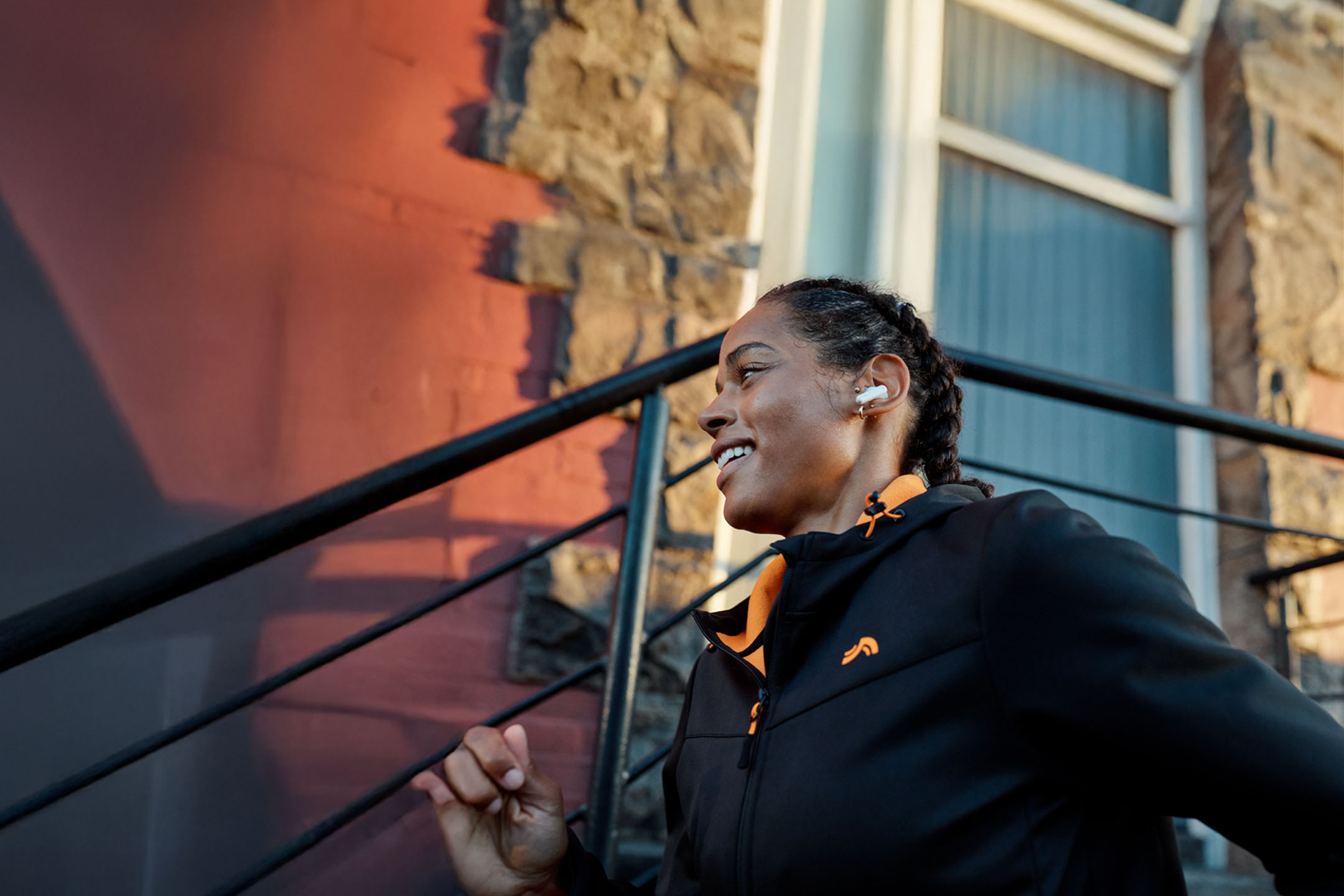 Kvinde løber med høretelefoner i en jakke.